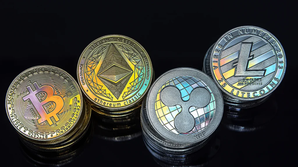 Moedas físicas de Bitcoin, Ethereum, XRP e Litecoin — criptomoedas especulativas, diferentes dos tokens de ativos com lastro real
